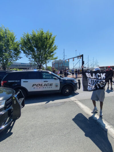 Protestor holds Black Lives Matter sign as he faces down Wilmington police.