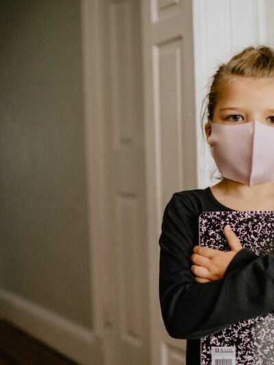 Child holding notebook with face mask on