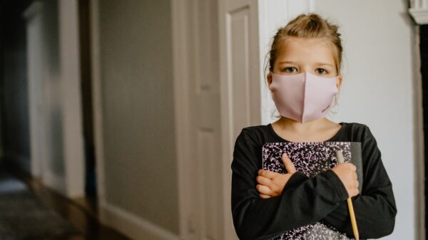 Child holding notebook with face mask on