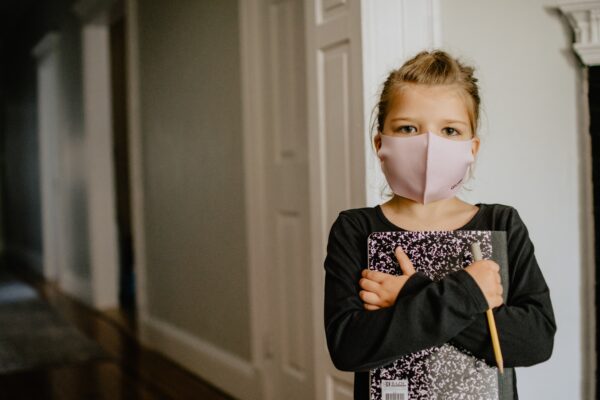 Child holding notebook with face mask on