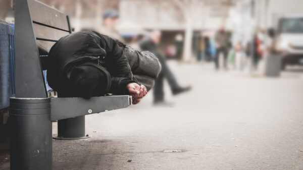 Homeless person sleeping on a bench in a city