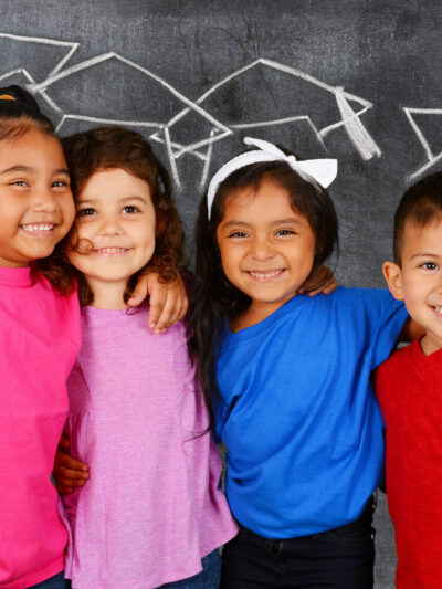 Young students standing in front of a chalkboard