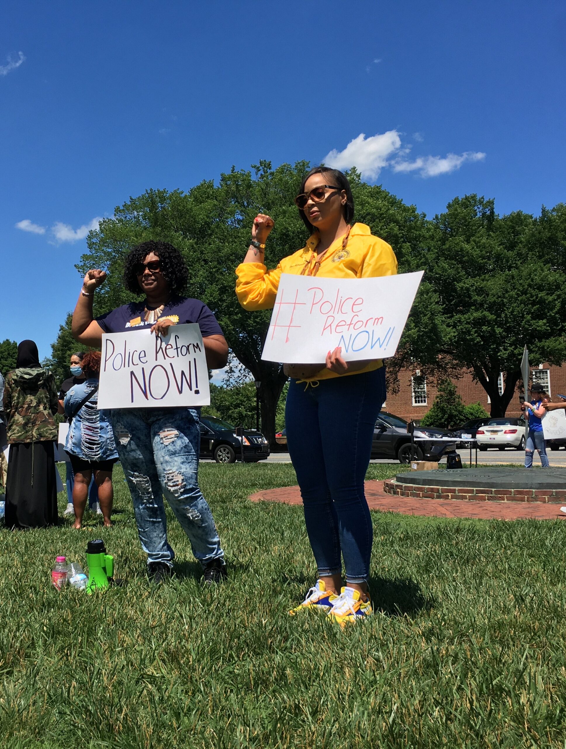 Two Black rally attendees holding handwritten police reform signs.