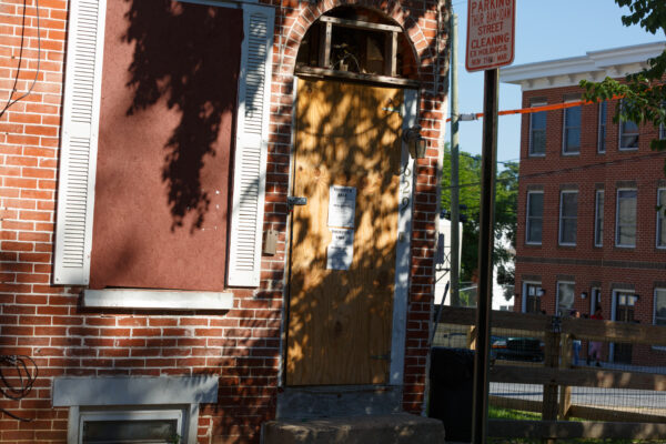 Boarded up house with notice on door