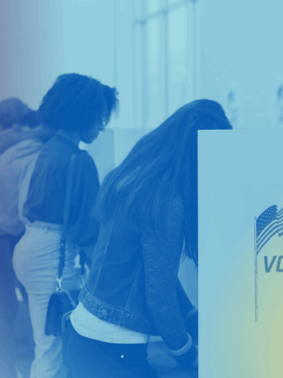 Voters fill out their ballots at voting cubicles in a school gym.