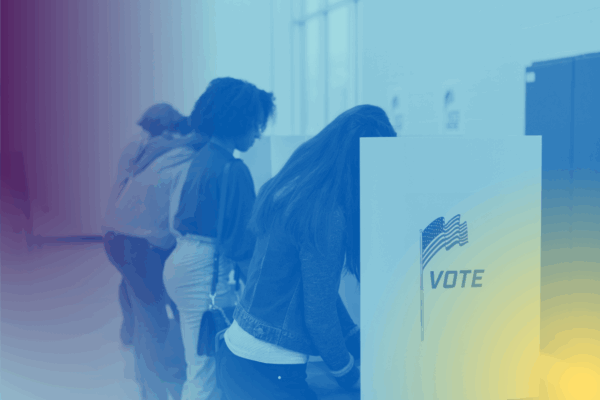 Voters fill out their ballots at voting cubicles in a school gym.
