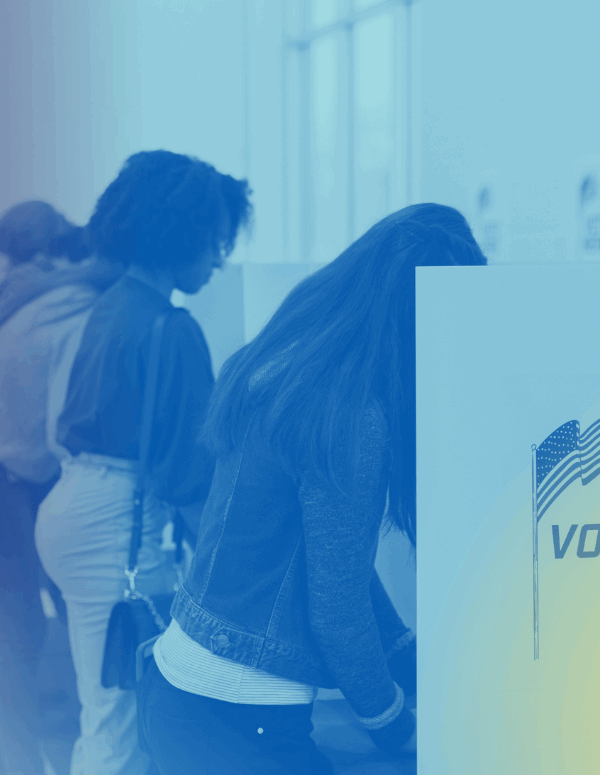 Voters fill out their ballots at voting cubicles in a school gym.