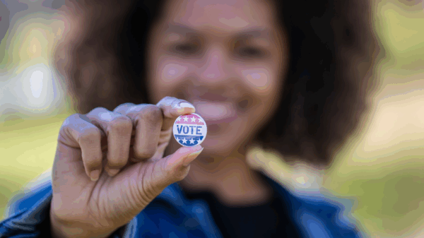 Woman holding VOTE pin