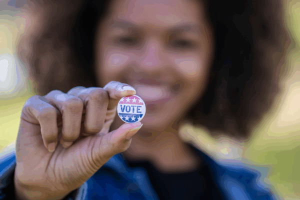 Woman holding VOTE pin
