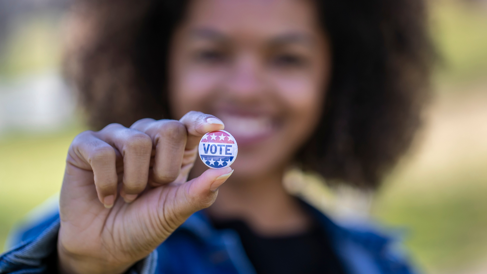 Woman holding VOTE pin