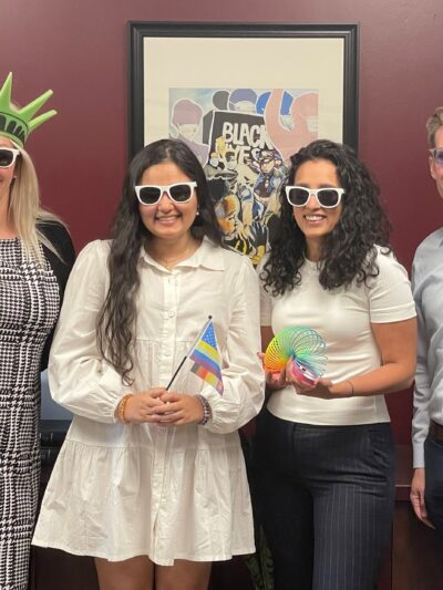 Photo of ACLU Delaware's legal team: Katie, Jasmine, Charmi, and Dwayne. They are wearing sunglasses and holding pride and patriotic swag.
