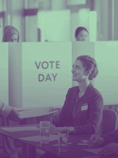 A person holding a paper form and talking to election officials.