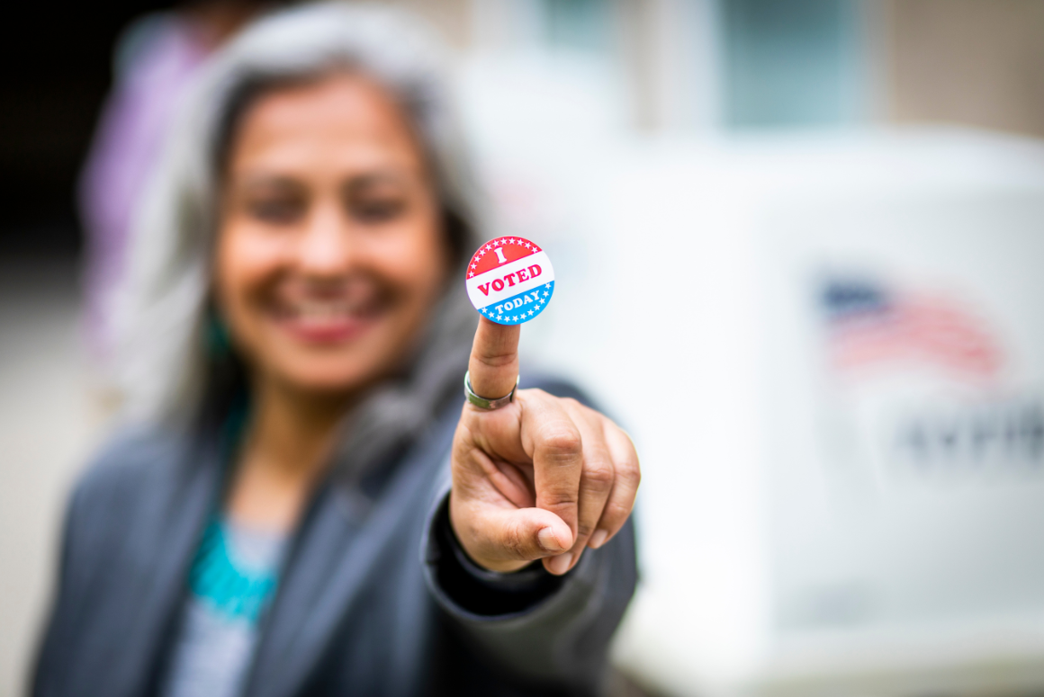 Woman holding "I Voted" sticker