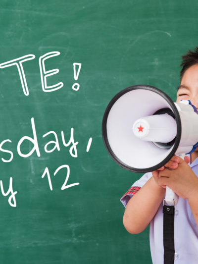 A kid with a megaphone stands in front of a chalkboard that reads "Vote! Tuesday, May 12"