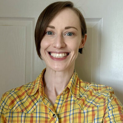 Jac Cichocki wearing a yellow plaid shirt and smiling in front of a white background
