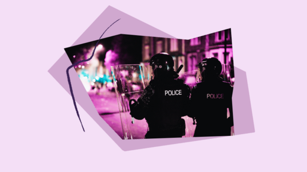 photo of two police officers standing in the street, in uniform, with helmets and shields