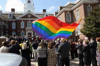 In a crowd gathered in front of the Delaware State Capitol building, an attendee's rainbow Pride flag blows in the wind.