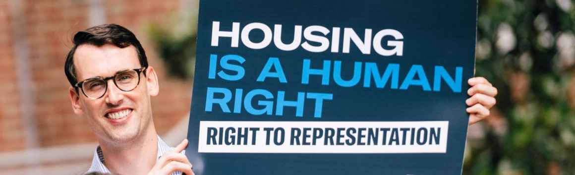 Man holding a sign that says "Housing is a Human Right"