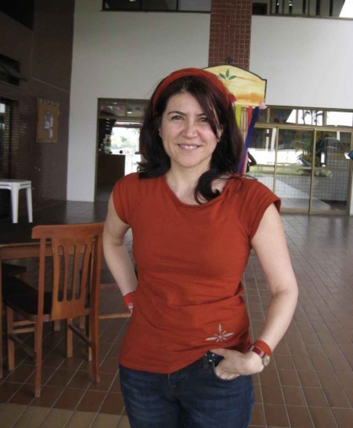 A photo of Carla Guerrón Montero wearing a red shirt and standing in front of a table.