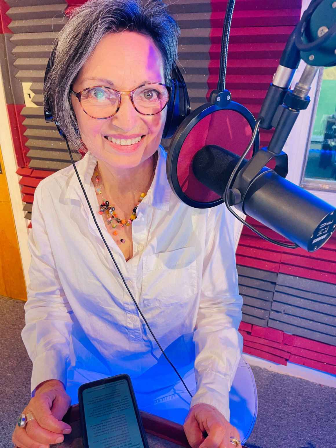 A photo of Charito Calvachi-Mateyko sitting at a microphone and wearing a headset.