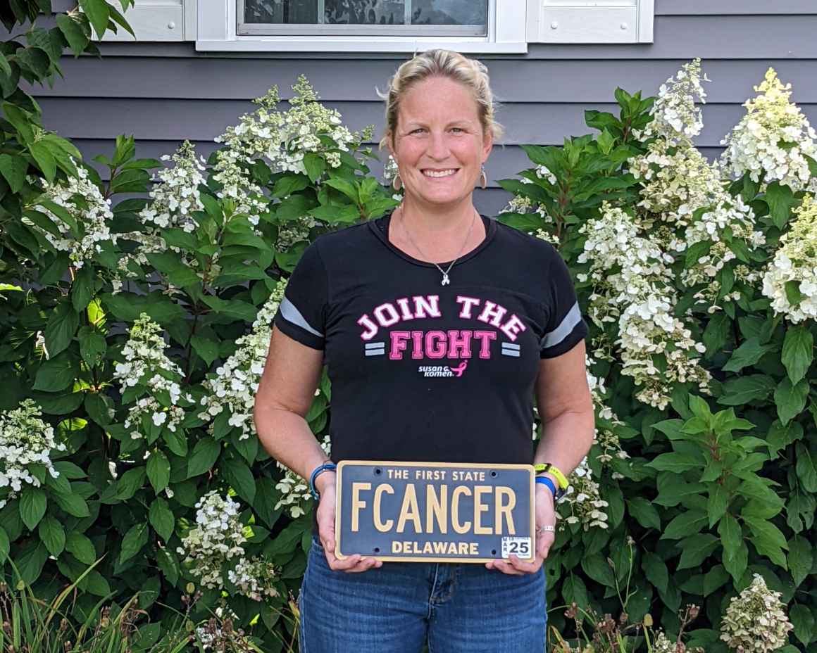 Photo of Kari Overington holding her "FCANCER" license plate.