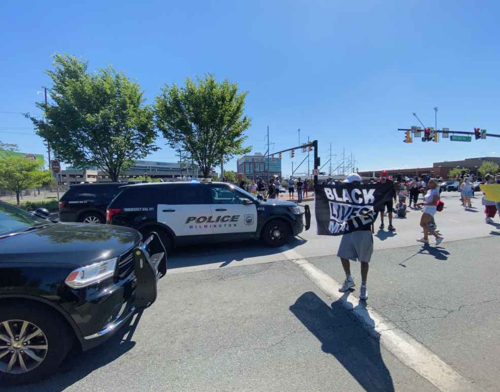 Protestor holds Black Lives Matter sign as he faces down Wilmington police.