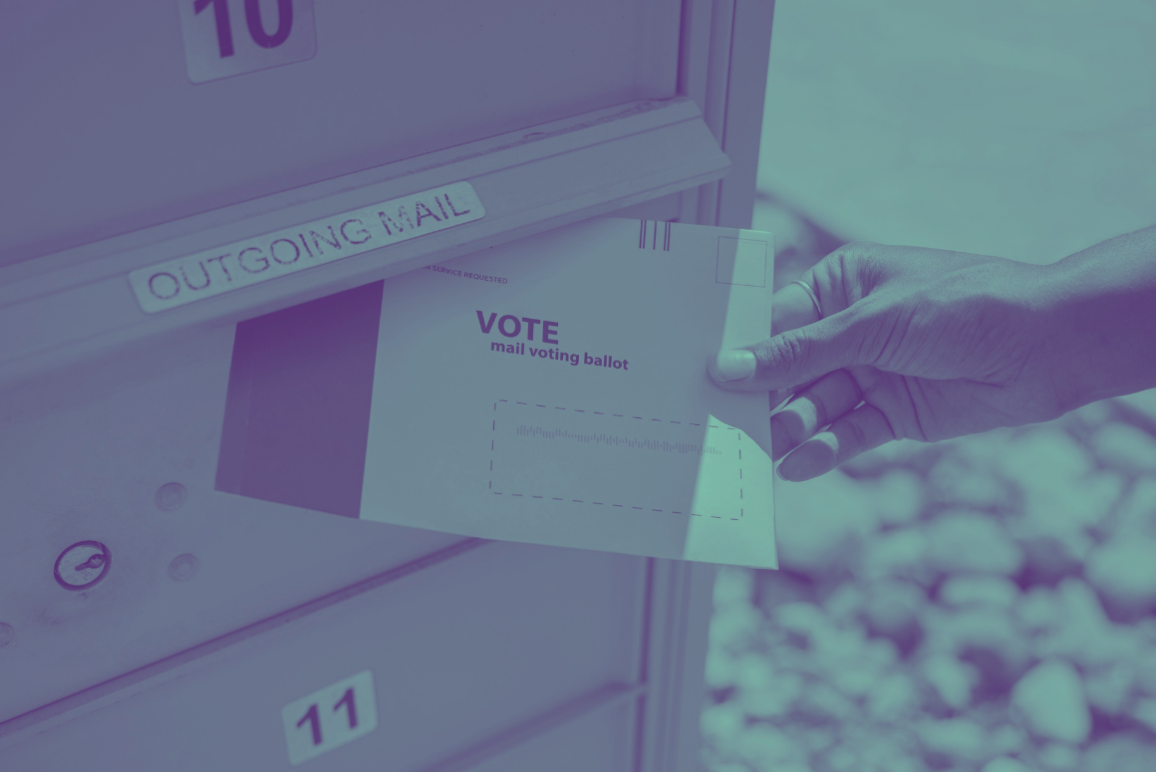 photograph of a person's hand putting a mail ballot in an "outgoing mail" mailbox.