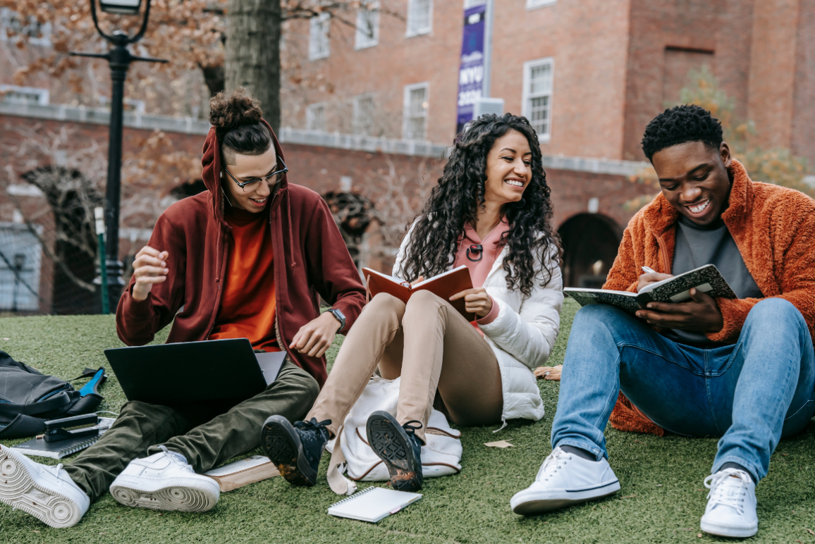 University students sitting on a campus lawn.