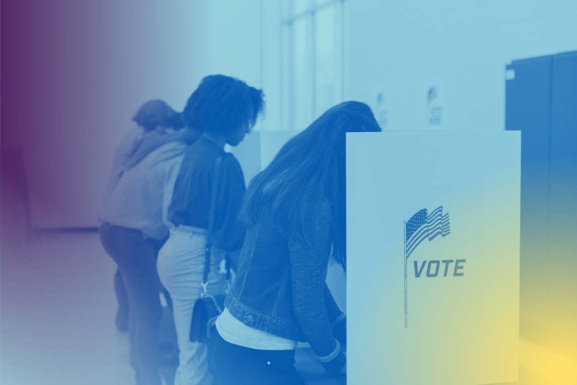 Voters fill out their ballots at voting cubicles in a school gym.