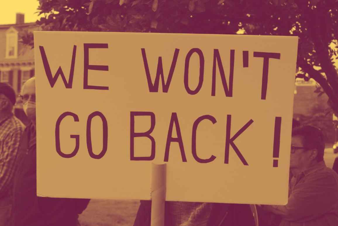 A protestor holding a sign saying, "We Won't Go Back."