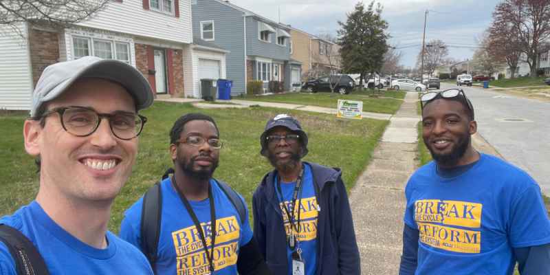 Four men in a suburban neighborhood with matching blue shirts