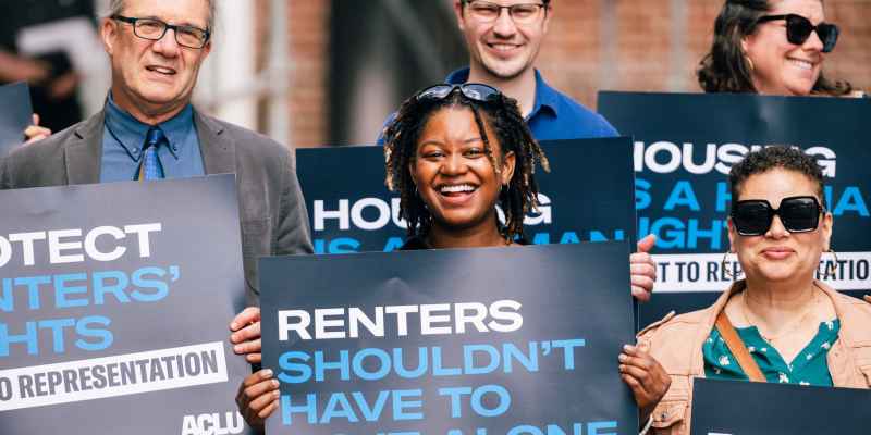 People holding signs that say "Renters shouldn't have to go it alone"