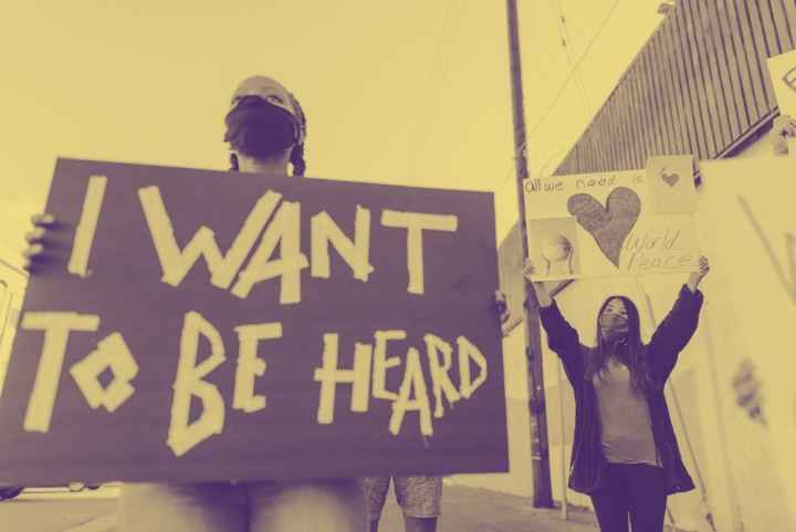 photograph of a person holding a sign that says "I want to be heard."