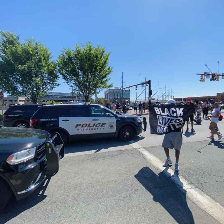 Protestor holds Black Lives Matter sign as he faces down Wilmington police.