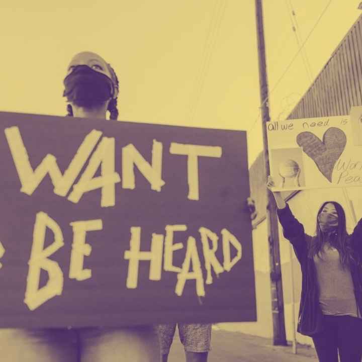 photograph of a person holding a sign that says "I want to be heard."