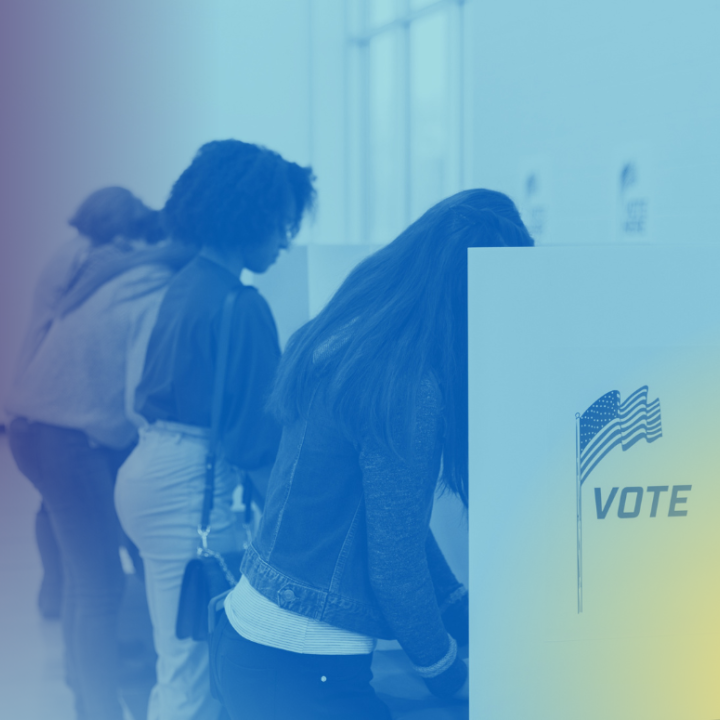 Voters fill out their ballots at voting cubicles in a school gym.