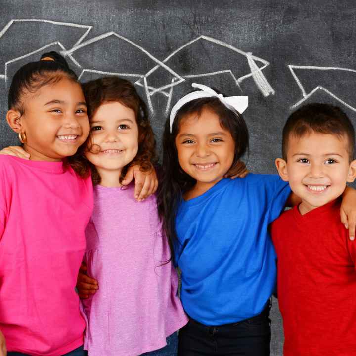 Young students standing in front of a chalkboard