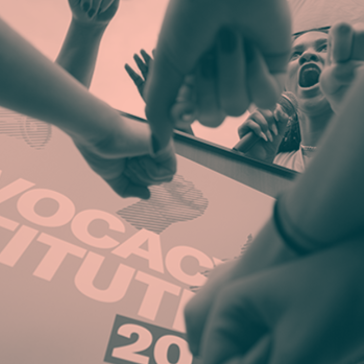A photo of an activist yelling into a microphone, surrounded by other activists.