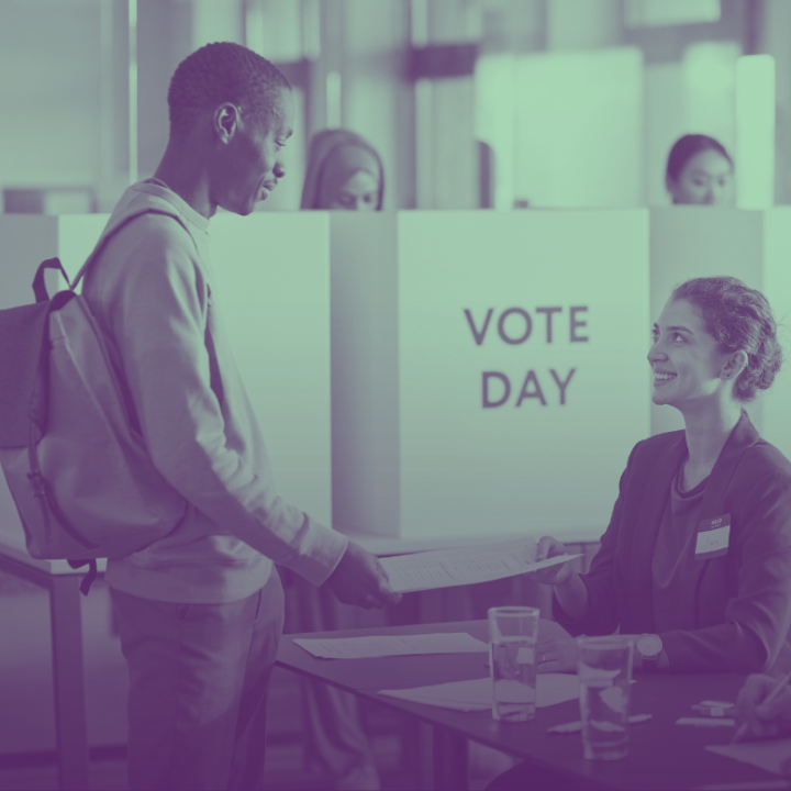 A person holding a paper form and talking to election officials.